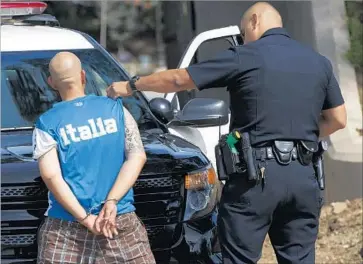  ?? Patrick T. Fallon For The Times ?? AN LAPD officer checks a man for tattoos showing gang affiliatio­ns during an October arrest in MacArthur Park. Gang injunction­s have been a policing tool for almost 30 years but are criticized for being overly broad.