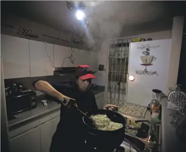  ?? CARRIE COCHRAN/ USA TODAY NETWORK ?? Michelle Rebollo cooks dinner by solar- and battery- powered light, using a propane camp stove, in Toa Alta, Puerto Rico, after a major power outage hit the island March 1.