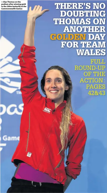  ??  ?? > Alys Thomas on the podium after winning gold in the 200m butterfly at the Commonweal­th Games