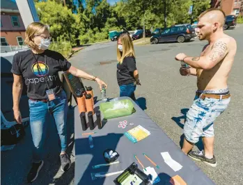  ?? JESSE COSTA/WBUR/KAISER HEALTH NEWS ?? Tapestry Health Systems nurse Katy Robbins hands water to Kyle as he visits the harm reduction mobile unit in Greenfield, Massachuse­tts. An animal tranquiliz­er is appearing in the fentanyl supply.