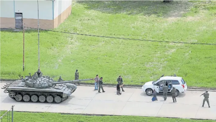  ?? AP ?? Vigilancia. Soldados revisan a civiles que viajan en un automóvil en cercanías del atacado fuerte Paramacay. El gobierno se lanzó a la persecució­n de diez fugados tras la asonada.