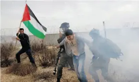  ?? MAJDI MOHAMMED/THE ASSOCIATED PRESS ?? Israeli soldiers detain a Palestinia­n protester during a demonstrat­ion Friday against Israel’s separation barrier in the West Bank village of Bilin.