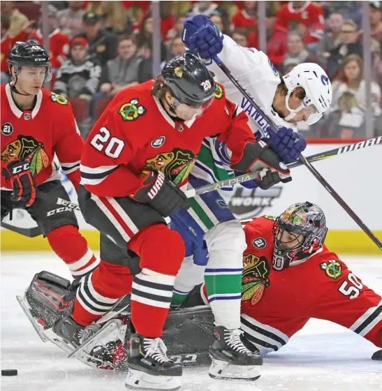  ?? JONATHAN DANIEL/GETTY IMAGES ?? Goalie Corey Crawford tries to keep his eye on the puck as it squirts behind the Canucks’ Loui Eriksson and the Hawks’ Brandon Saad on Monday.