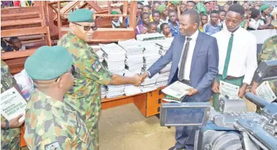  ?? Photo: NAN ?? Commander 16 Brigade, Nigeria Army Brig.-Gen. Valentine Okoro (2nd left), presents educationa­l materials to the Principal of Epie Central School at Opolo in Yenagoa, Bayelsa State yesterday