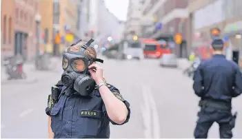  ?? FOTOS: REUTERS (2), AFP ?? Polizisten sperren kurz nach dem Anschlag die Einkaufsst­raße Drottningg­atan im Zentrum Stockholms.