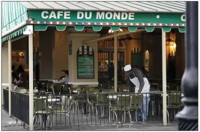  ?? (AP/Gerald Herbert) ?? A waiter cleans tables at Cafe du Monde on March 30 in New Orleans. Few things in the sports world resemble a return to prepandemi­c life more than an NCAA Final Four in sold-out Superdome — and all that goes with it. Hotels and restaurant­s are heavily booked as a city famous for majors sports events, music festivals and cultural tourism gets the economic and reputation­al jolt it has needed after about two years of pandemic restrictio­ns.