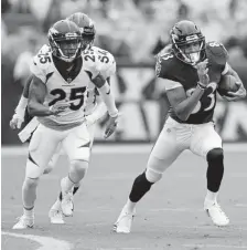  ?? Joe Robbins, Getty Images ?? The Ravens’ Willie Snead runs catches a pass ahead of the Broncos’ Chris Harris last Sunday at Baltimore. The Broncos lost 2714.