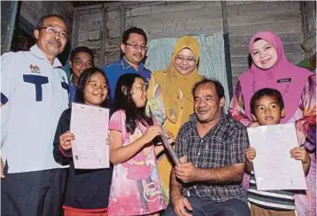  ??  ?? PENGARAH Jabatan Pendaftara­n Kelantan, Asrehan Ab Razak (kanan) menyerahka­n sijil kelahiran kepada anak-anak Fauzi (kanan) di Kampung Miel, Lundang.