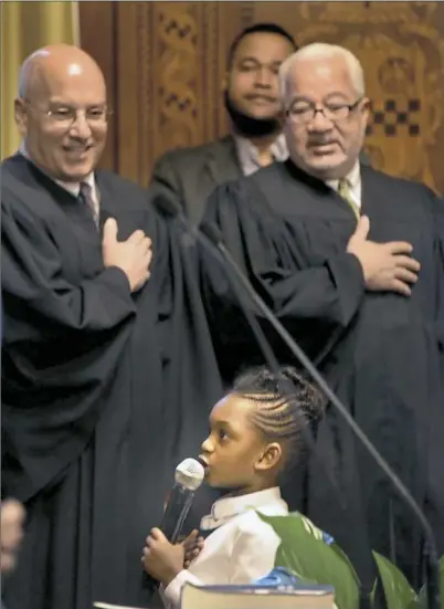  ??  ?? Saniya Lavelle, 6, daughter of Councilman Daniel Lavelle, recites the Pledge of Allegiance on Wednesday before council swearing-in ceremonies at the City-County Building, Downtown. District Judge James Motznik, left, and Judge Joseph Williams of Common...