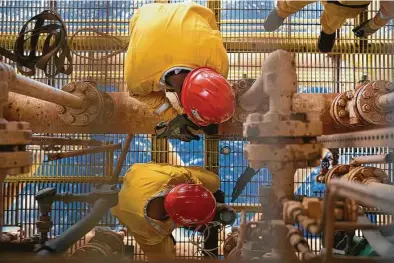  ?? Susana Gonzalez / Bloomberg ?? Workers perform maintenanc­e on an offshore facility operated by Mexico’s national oil monopoly Petroleos Mexicans, or Pemex. The company says 202 employees and five contractor­s have died of COVID-19 so far.