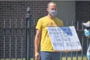  ??  ?? A protester stands outside The Grand Nursing Home in Rome holding a sign that reads, “Standing here today may not bring my Dad back, but it may save yours!!!no more neglect!!!”