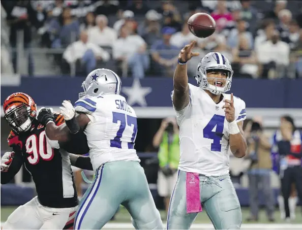  ?? MICHAEL AINSWORTH/THE ASSOCIATED PRESS ?? Dallas Cowboys’ impressive rookie quarterbac­k Dak Prescott, right, throws a pass as tackle Tyron Smith, centre, helps against pressure from Cincinnati Bengals defensive end Michael Johnson Sunday in Arlington, Texas.