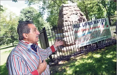  ?? Arnold Gold / Hearst Connecticu­t Media ?? Peter Criscuolo speaks about the temporary All Lives Matter sign containing the flags of 147 nations hanging from the fence surroundin­g the base of the former statue of Christophe­r Columbus on Wooster Square in New Haven on Thursday.