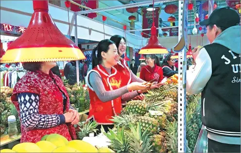  ?? PHOTOS PROVIDED TO CHINA DAILY ?? A resident tries pineapples at a marketplac­e in Changchun, capital of Jilin province, during Spring Festival. People’s livelihood­s have improved in the past year with per capita disposable income for the province’s urban and rural residents up 6.5...