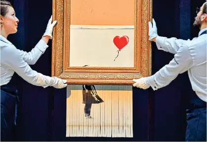  ?? Picture: AFP/Getty Images ?? Self-shredding: Banksy’s ‘Girl With Balloon’ after it sold at Sotheby’s in 2018