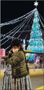  ?? (AP/Juan Karita) ?? An Aymara woman talks on her cellphone Dec. 13 at the Tejada Sorzano square adorned with holiday lights in La Paz, Bolivia.