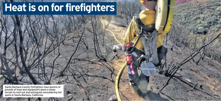  ??  ?? Santa Barbara County firefighte­rs haul dozens of pounds of hose and equipment down a steep terrain to root out and extinguish smoulderin­g hot spots in Santa Barbara, California.