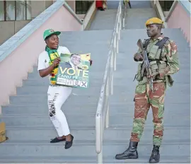  ?? Picture: Reuters ?? SHOW OF SUPPORT. A Zanu-PF supporter holds a poster in front of a soldier ahead of a rally in Harare on Saturday.