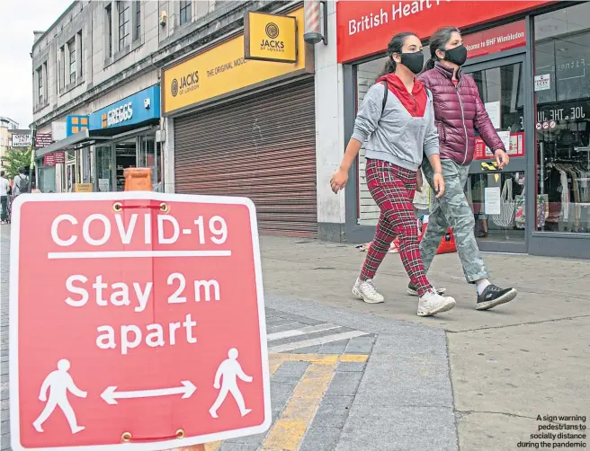  ??  ?? A sign warning pedestrian­s to socially distance during the pandemic