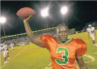  ?? MICHAEL LAUGHLIN/STAFF FILE PHOTO ?? Tyrone Moss raises the ball he carried to a single season rushing record at Blanch Ely High school of 2,011 yards in 2000.