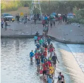  ?? PAUL RATJE/GETTY-AFP ?? Haitian migrants cross the Rio Grande on Saturday to get food and supplies near the Del Rio-Acuna Port of Entry in Ciudad Acuna, Coahuila state, Mexico.