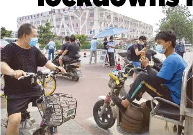  ??  ?? People stop at a checkpoint outside the Xinfadi wholesale food market district in Beijing yesterday after the discovery of new COVID-19 cases in the area.