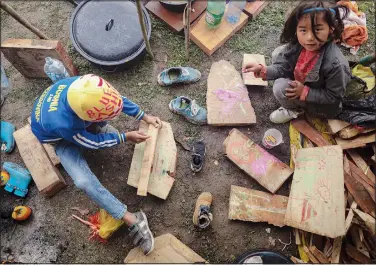  ?? ?? Migrant children draw on pieces of wood at a makeshift camp housing migrants, mostly from Afghanista­n, in Velika Kladusa.