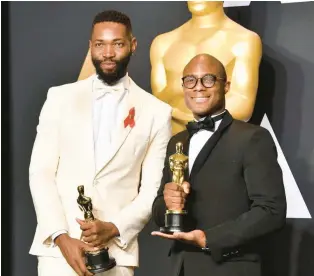  ?? FRAZER HARRISON /GETTY ?? Screenwrit­er Tarell Alvin McCraney and director Barry Jenkins, of “Moonlight,” hold their Academy Awards. In 2017, “Moonlight” became the first LGBTQ film to win an Oscar for Best Picture.