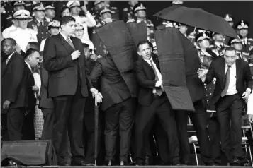  ?? ASSOCIATED PRESS ?? IN THIS PHOTO RELEASED by China’s Xinhua News Agency, security personnel surround Venezuela’s President Nicolas Maduro during an incident as he was giving a speech in Caracas, Venezuela, Saturday. Drones armed with explosives detonated near Venezuelan President Nicolas Maduro as he gave a speech to hundreds of soldiers in Caracas on Saturday but the socialist leader was unharmed, according to the government.