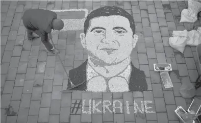  ?? ARMEND NIMANI/GETTY-AFP ?? Kosovo artist Alkent Pozhegu works on a portrait of Ukrainian President Volodymyr Zelenskyy made with grain and seed Tuesday in Kosovo. Over the past week, Zelenskyy emerged as the everyman leader.