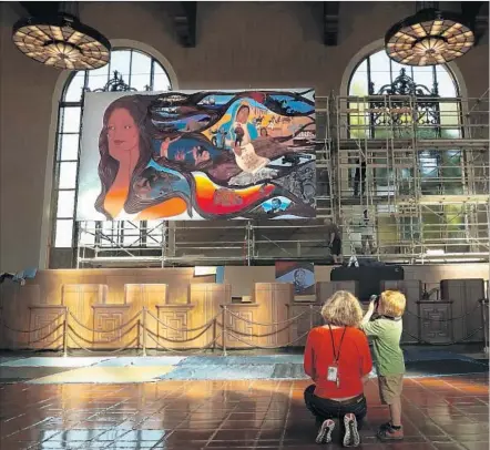  ?? Photograph­s by Mel Melcon Los Angeles Times ?? JESSICA HOUGH and son Ansel, 4, watch the installati­on of Barbara Carrasco’s mural in the former ticket concourse at the station.