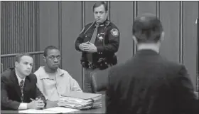  ?? NEWS-HERALD FILE ?? Jeff Cook, right, the brother of the late Edmund Roland shows a photograph of Roland to his killer, Mario Redding, center, along with defense attorney Paul Daiker after reading a prepared statement during Redding’s sentencing in November 2007, in the Cuyahoga County Common Pleas courtroom of Judge Richard Ambrose in Cleveland.