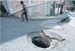  ?? FOTO: DAVID ROMERO ?? Para alertar del agujero a peatones y conductore­s, vecinos del lugar han colocaron piedras, llantas y todo tipo de indicadore­s.