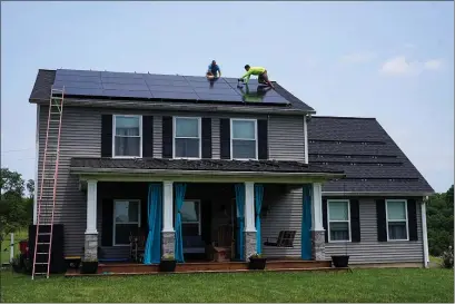  ?? MICHAEL CONROY, FILE — THE ASSOCIATED PRESS ?? The author writes that to date, low-income and disadvanta­ged households have been left behind in the rapid deployment of residentia­l distribute­d solar generation. Above, solar panels are installed on the roof of a home in Frankfort, Ky. last summer.