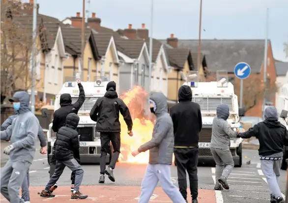  ?? CHARLES MCQUILLAN/GETTY ?? Amid a recent spate of violence, people attack police vehicles Thursday near gates dividing nationalis­t and loyalist communitie­s in Belfast, Northern Ireland.