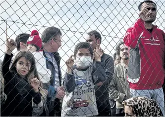  ?? GETTY IMAGES ?? Migrants and children stand behind a fence at the Hellinikon camp in Athens, Greece, on Monday, in a protest at poor living conditions. A new study on Canadians views on refugees and immigratio­n found that there is potential for intolerant,...