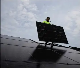  ?? MICHAEL CONROY - THE ASSOCIATED PRESS ?? Nicholas Hartnett, owner of Pure Power Solar, holds a panel as his company installs a solar array on the roof of a home in Frankfort, Ky., on July 17.