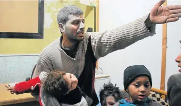  ?? /AFP Photo ?? Innocents killed: A Syrian man holds a child at a makeshift hospital in Douma. The child was wounded on Monday in air strikes on the Syrian village of Mesraba in the besieged Eastern Ghouta region on the outskirts of the capital, Damascus.