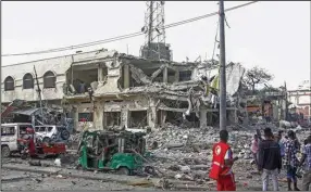  ?? (AP/Farah Abdi Warsameh) ?? People observe a destroyed building and vehicles at the scene of two car bomb attacks Saturday in Mogadishu, Somalia.