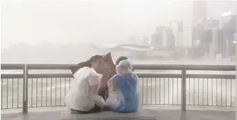  ??  ?? Des curieux ont bravé la tempête, au quai Victoria de Hong Kong, mercredi. Associated Press: Vincent Yu