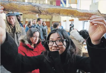  ?? CLIFFORD SKARSTEDT EXAMINER ?? Trent University student Ellie Tamura inspects a bronze sword as Jordan Dills and Patrick Kenny conducted a bronze sword-casting demonstrat­ion at Trent University’s Great Hall.