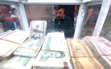  ??  ?? A man counts Iranian rials at a currency exchange shop, before the start of the US sanctions on Tehran, in Basra, Iraq. — Reuters photo