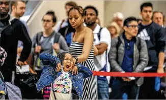  ?? JOHN SPINK / JSPINK@AJC.COM ?? The long holiday lines at Hartsfield-Jackson Internatio­nal Airport on Thursday morning take their toll on Milani Kinos, 4, with her mother, Michelle Rustin, from New York.