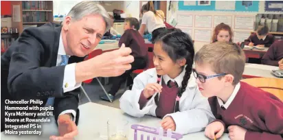  ??  ?? Chancellor Philip Hammond with pupils Kyra McHenry and Oli Moore at Rowandale Integrated PS in Moira yesterday