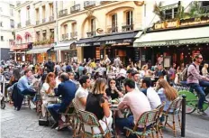  ??  ?? People eat and have drinks on restaurant and cafe terraces in Paris.