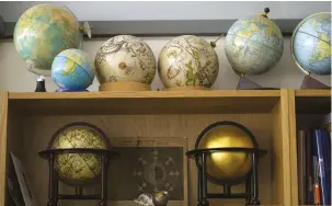  ??  ?? ABOVE Globes old and new adorn the shelves in Sylvia’s south London studio FACING PAGE Wearing a headband magni er to leave her hands free for the delicate task, Sylvia gently rolls a swab over the surface of an antique globe to remove the centuries of...