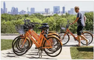 ?? RALPH BARRERA / AMERICAN-STATESMAN ?? Mark Nathan, a consultant with Spin dockless rental bicycles, which has started a pilot program with St. Edward’s University, parks some of the company’s bright orange bikes in front of the Main Building on the St. Edward’s campus Thursday.