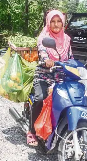  ?? — Bernama ?? Rain or shine: Zaharah on her motorbike, which she typically loads with a wide variety of foodstuffs to be offered for sale in all weather.