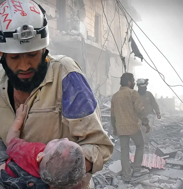  ??  ?? Casualty of war: A child is carried from the rubble after a bomb attack in Aleppo