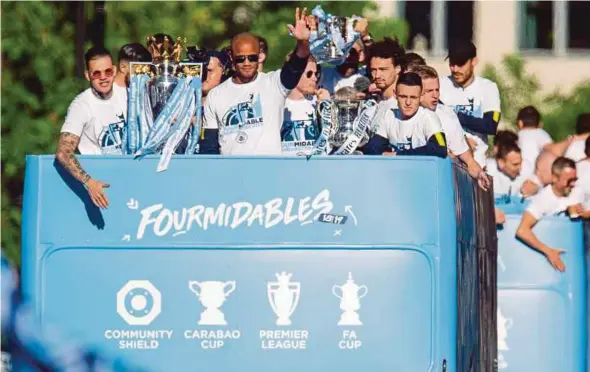  ?? EPA PIC ?? Manchester City goalkeeper Ederson (left) and Vincent Kompany hold the Premier League trophy on top of the bus during the Champions Parade on Monday.